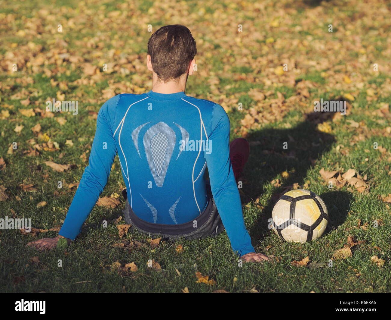 Fußball-Spieler posiert mit Fußball im Park an einem sonnigen Herbsttag Stockfoto