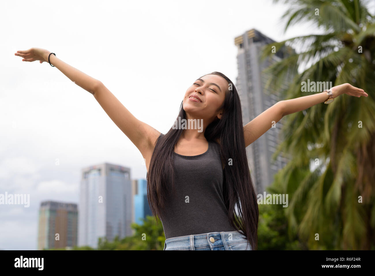 Junge schöne asiatische Frau Entspannung im Park mit erhobenen Armen Stockfoto