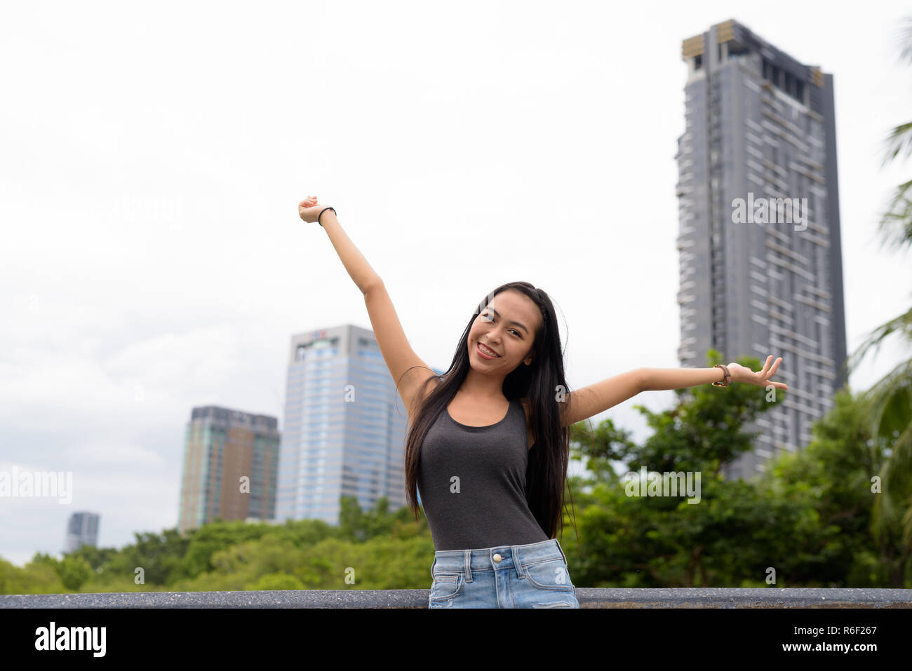 Junge schöne asiatische Frau Entspannung im Park mit erhobenen Armen Stockfoto