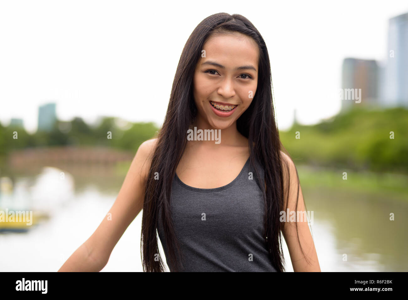 Glückliche junge schöne asiatische Frau im Park lächelnd Stockfoto