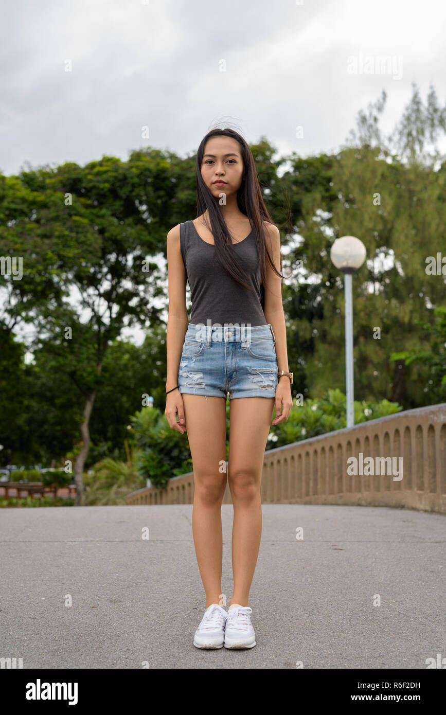 Die volle Länge der junge schöne asiatische Frau Entspannung im Park Stockfoto