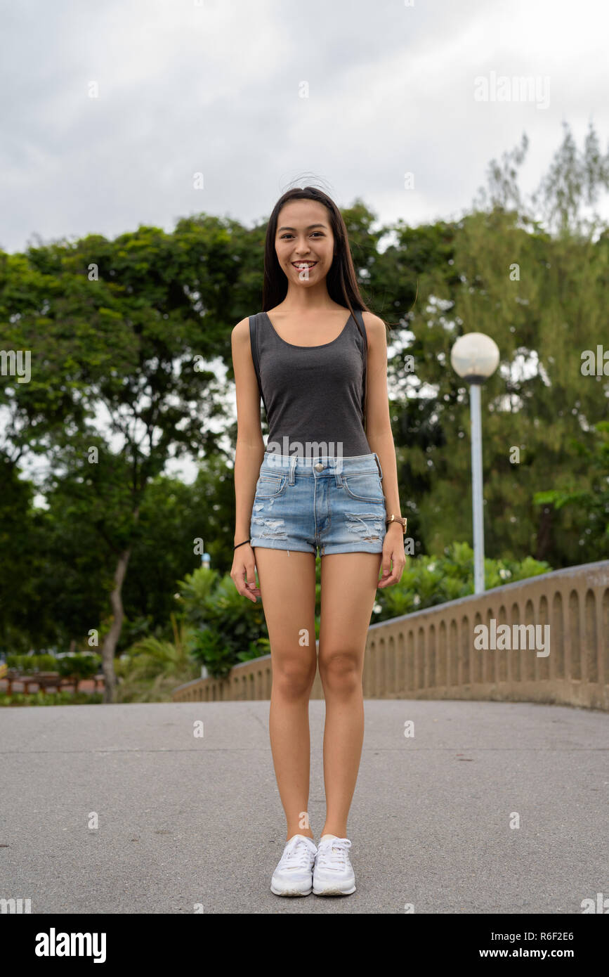 Die volle Länge der junge schöne asiatische Frau Entspannung im Park Stockfoto