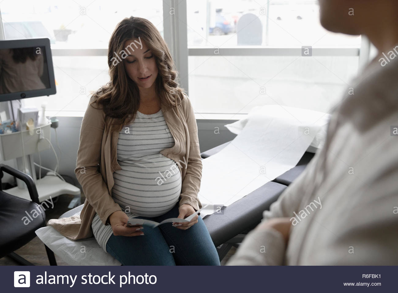 Schwangere Frau überprüfung Broschüre in Klinik Untersuchungsraum Stockfoto