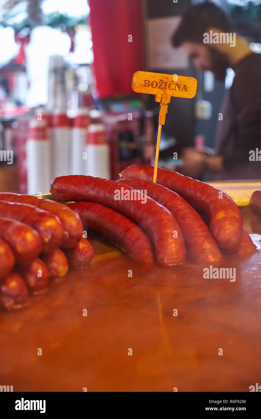 Weihnachten Würste (Bozicna) durch Kochen am Adventmarkt in Zagreb vorbereitet. Anzeigen der Verkäufe Person im Hintergrund verschwommen Stockfoto