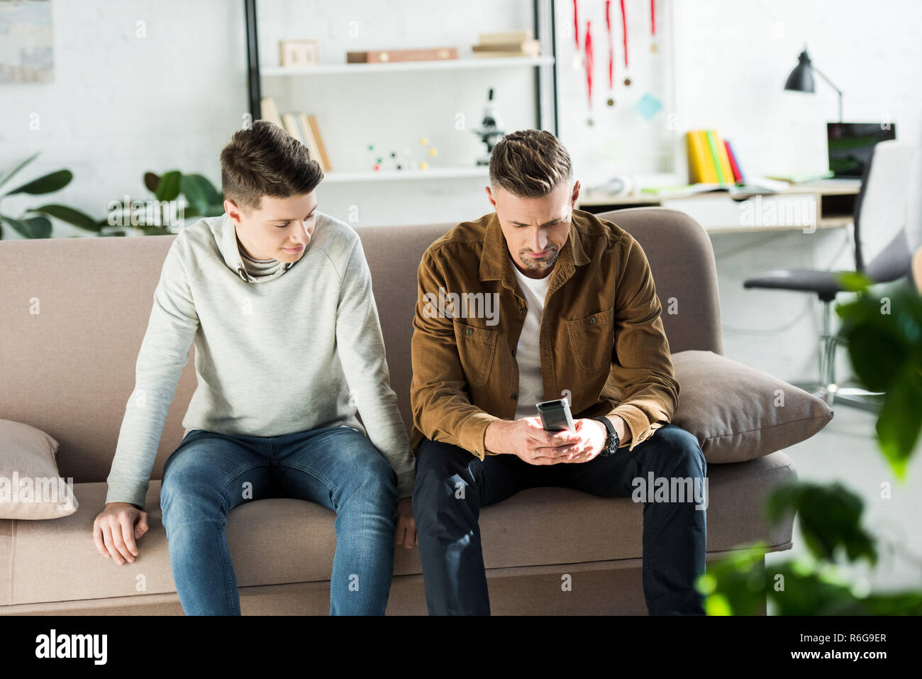 Vater und jugendlich Sohn sitzen auf dem Sofa und Fernbedienung Stockfoto
