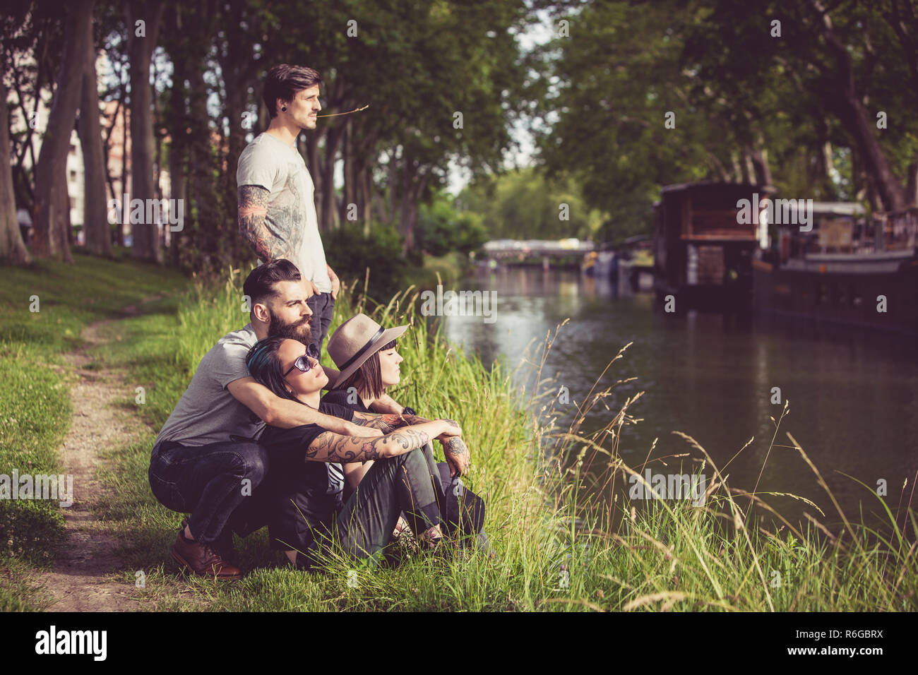Gruppe junger Hipster an den Ufern der Garonne, Schleppkähne im Hintergrund Stockfoto