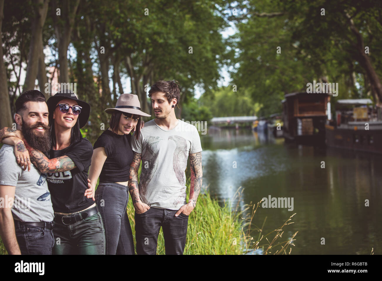 Gruppe junger Hipster an den Ufern der Garonne, Schleppkähne im Hintergrund Stockfoto