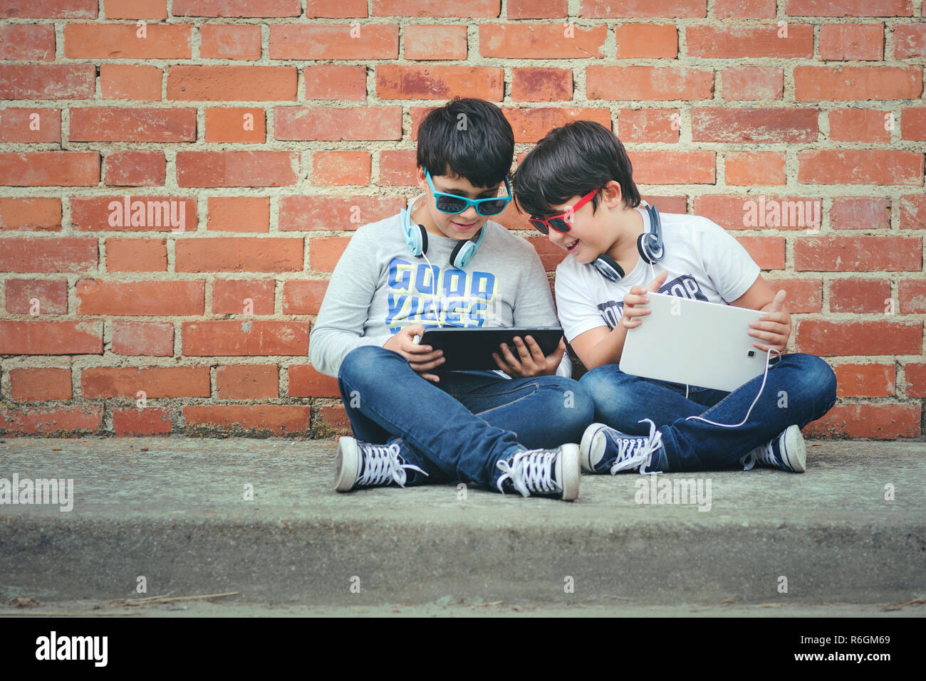 Kinder mit Kopfhörern mit digitalen Tablet in der Straße verbunden Stockfoto