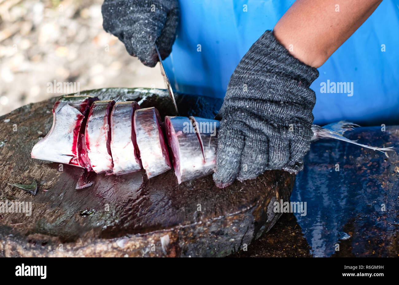 Ein Fisch Verkäufer verwendet, scharfen Messer schneiden frischen Fisch für Kunden Stockfoto