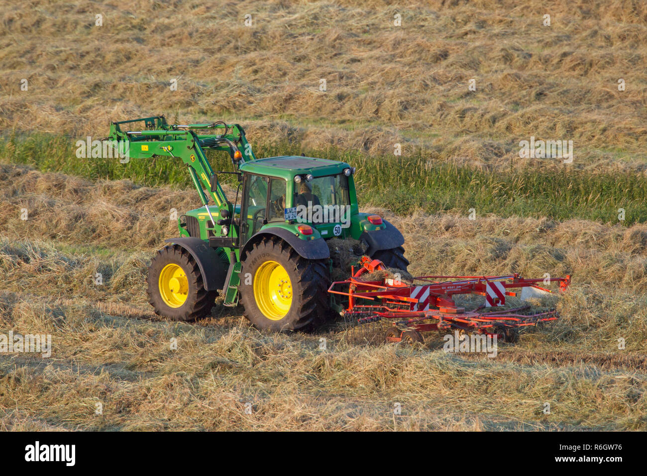 Traktor mit Rotary Heu rechen/gyrorake, entworfen, um das Heu zu Flusen und es über, so dass es bei der Heuernte im Sommer trocken Mai drehen Stockfoto