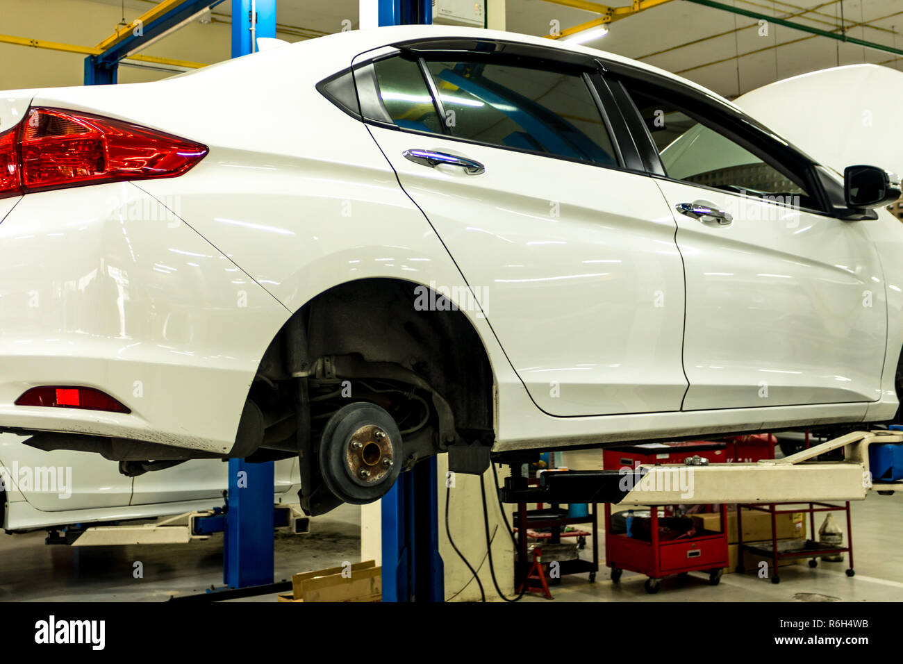 Weißes Auto gewartet wird, Auto auf der Hebebühne, Reparatur Auto Stockfoto