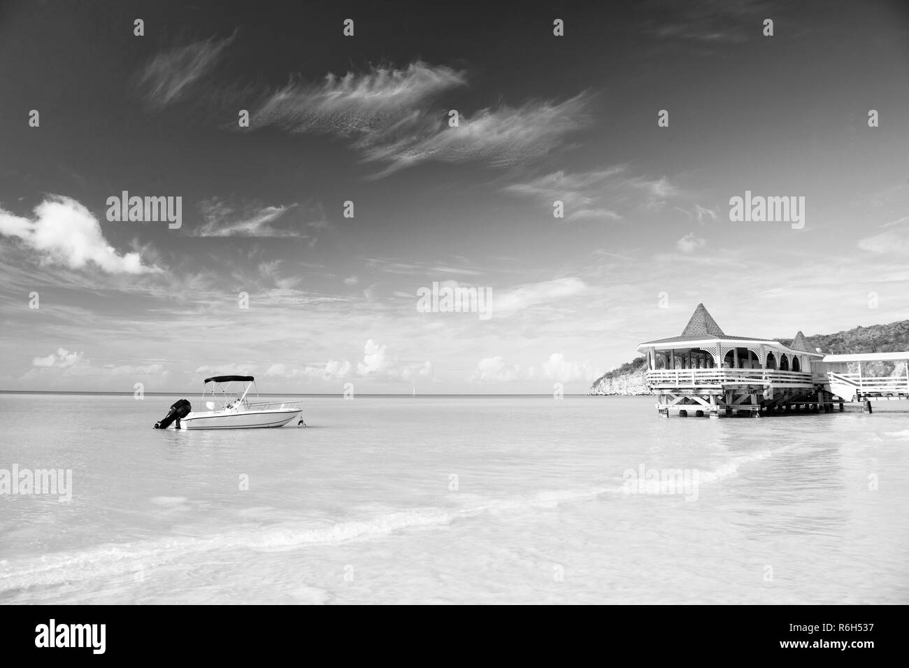 Genießen Sie die Vorteile, neben dem Meer. Meer türkisfarbenes Wasser Bungalow und Schiff in der Nähe von Strand. Ferienhäuser Meer Sandstrand tropischen Haus bungalow St Johns Antigua. Idyllischer sonniger Tag am Meer blauer Himmel. Stockfoto