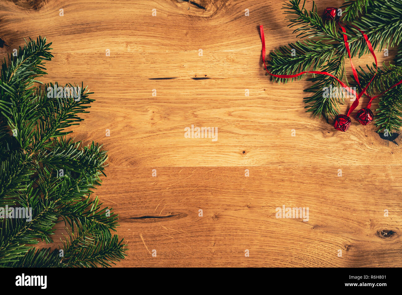Weihnachten Hintergrund mit Tannenbaum, rot glänzend Glocken auf braune Holztisch. Startseite flache Ansicht mit kopieren. Stockfoto