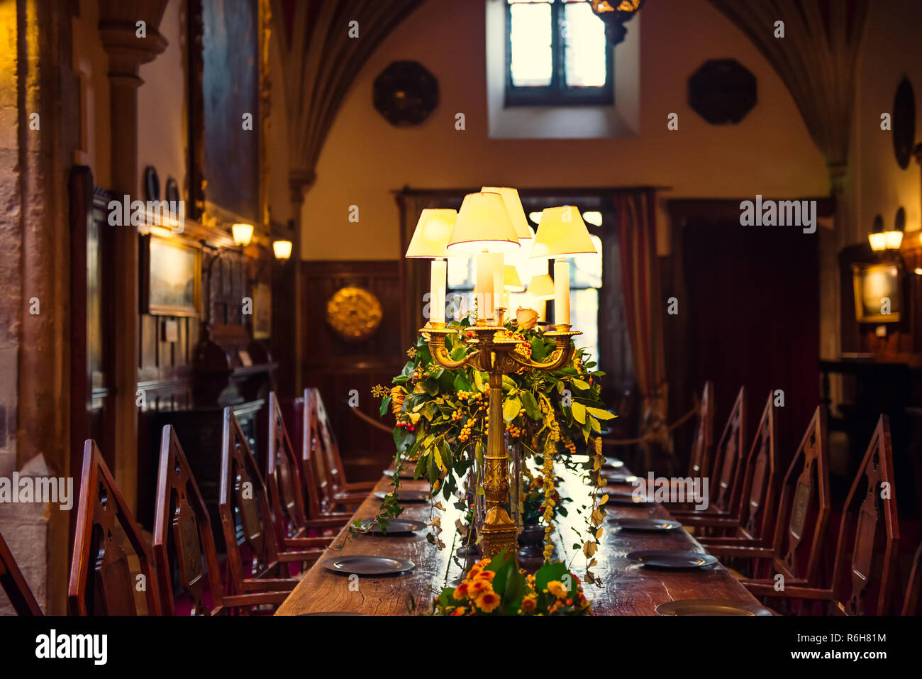Mittelalterliche britischen schloss Innenbereich Esstisch mit Platten, die Blumen und die Lampen. Warmes Licht. Selektiver Fokus. Kopieren Sie Platz Stockfoto