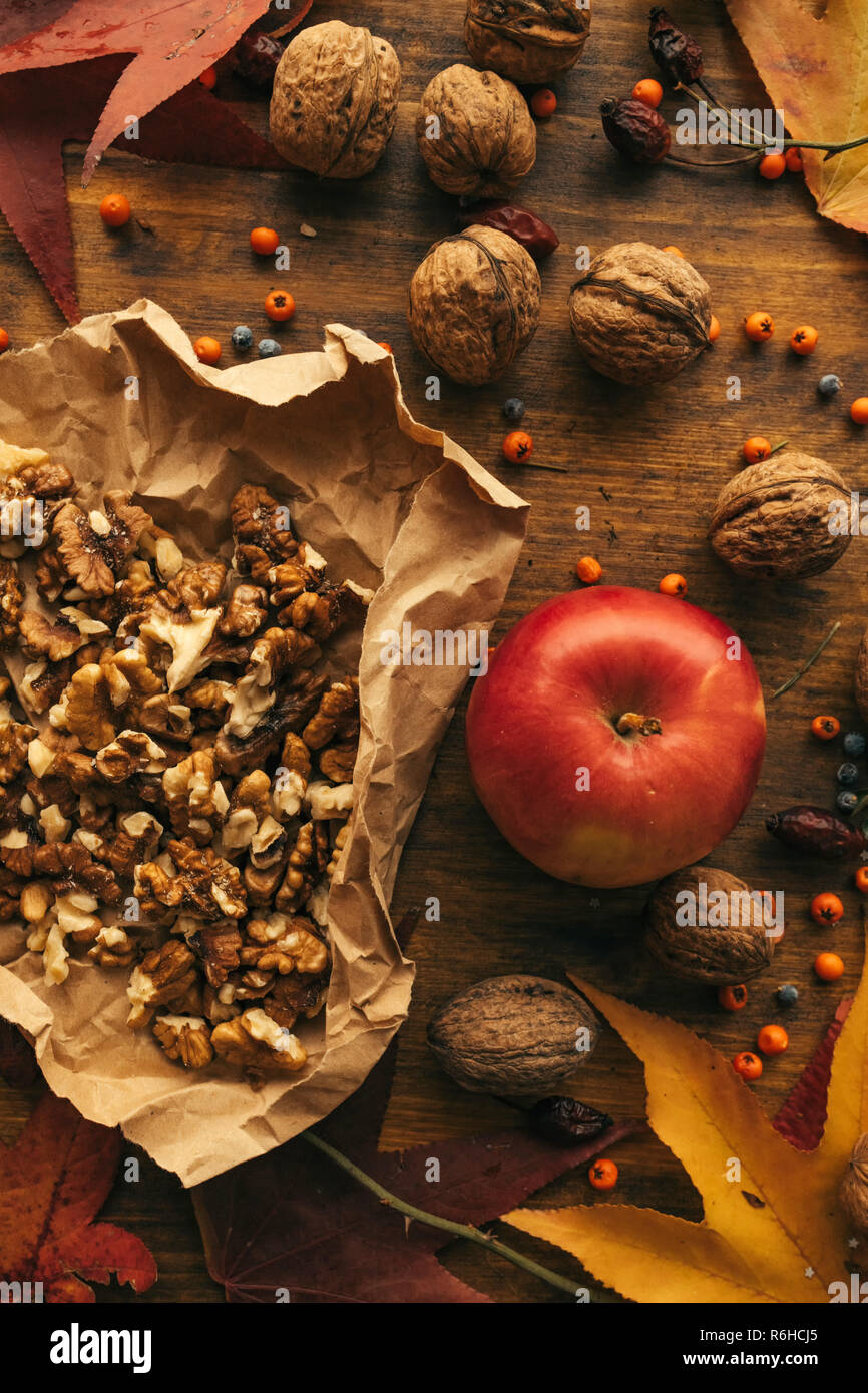 Apple und Nussbaum, Herbst Fülle - gesundes Bio-obst auf Holztisch mit bunten Ahorn Blätter und Beeren, Ansicht von oben eingerichtet Stockfoto