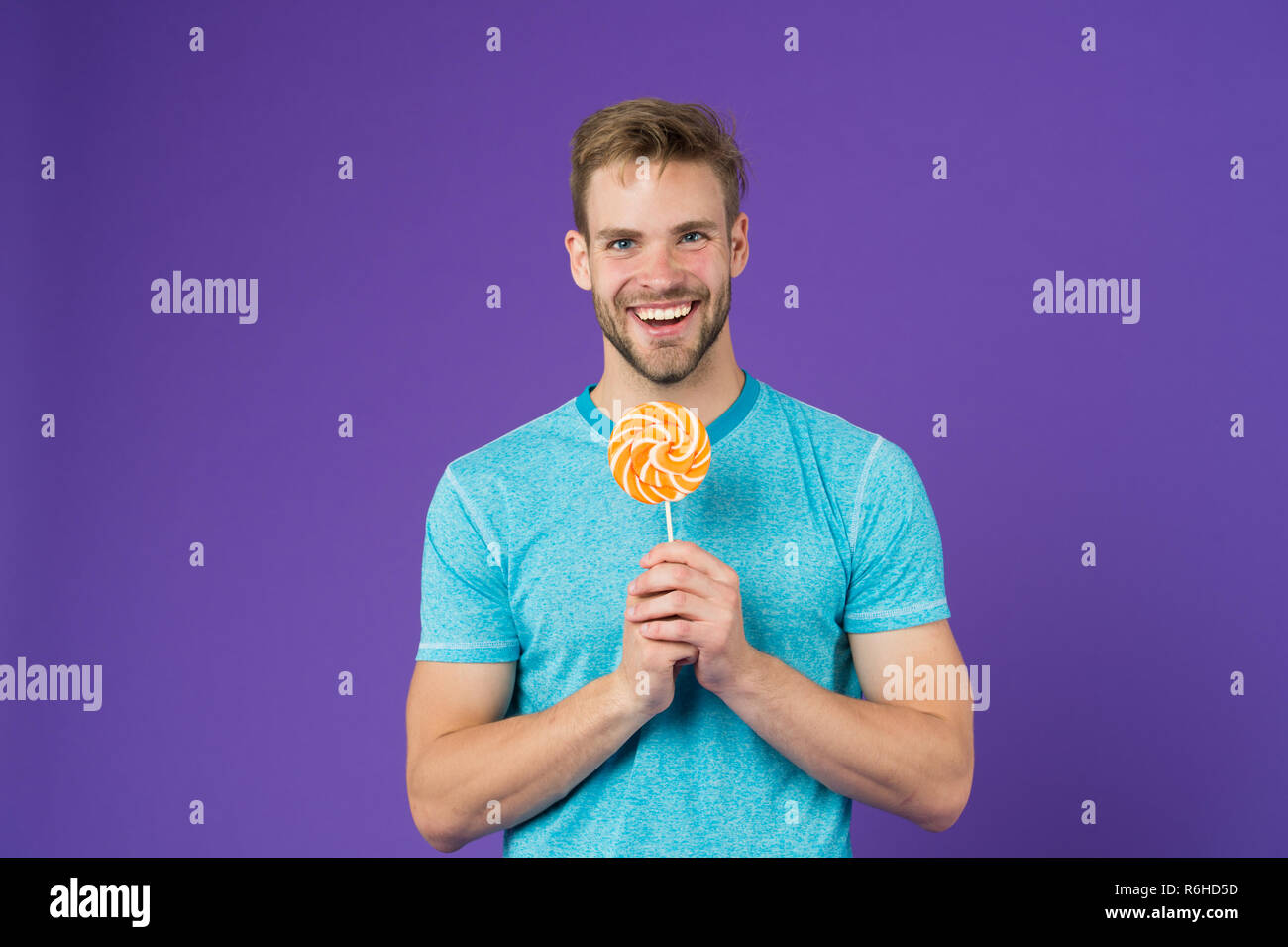 Geschmack der Kindheit. Mann mit Borsten mag Lollipop. Cheat meal Konzept. Zucker schädlich für die Gesundheit. Kerl halten Lollipop candy violett unterlegt. Mann schöner macho Essen großen bunten süßen Lutscher. Stockfoto