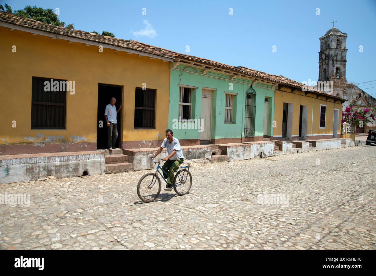 Eine kubanische Mann Zyklen einer gepflasterten Straße in Trinidad Kuba Vergangenheit traditionellen kubanischen Häuser Stockfoto