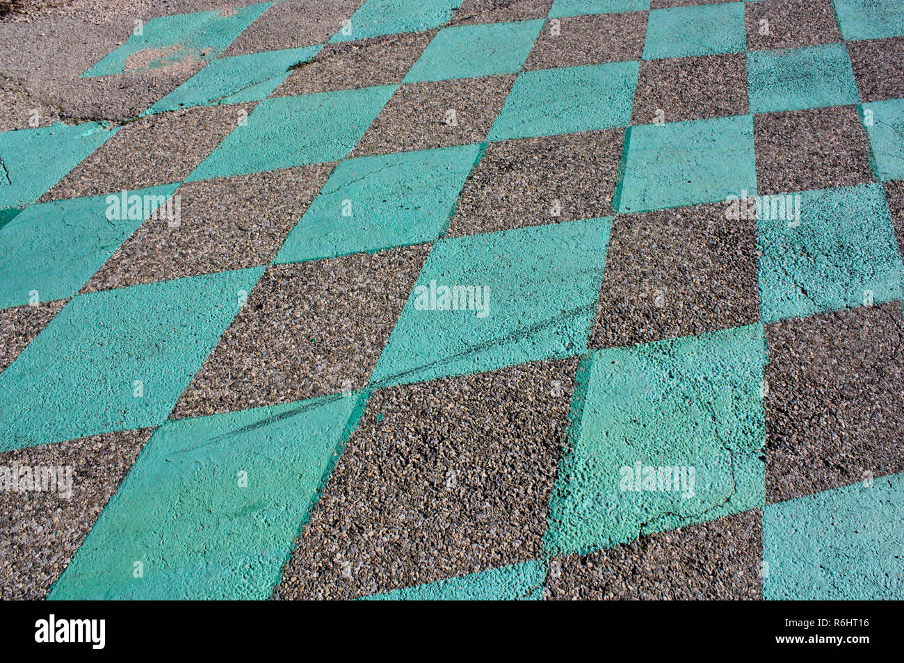 Muster der grüne Quadrate auf dem Asphalt. Sieht aus wie Racing Finish Line. Rauhe Teer, Schmutz und grüner Farbe. Stockfoto