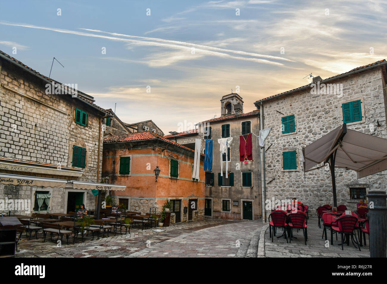 Eine übergrosse Anzeige der Wäsche hängt über einem kleinen Dorfplatz mit Cafés und Außenbereich in der mittelalterlichen Stadt Kotor, Montenegro. Stockfoto