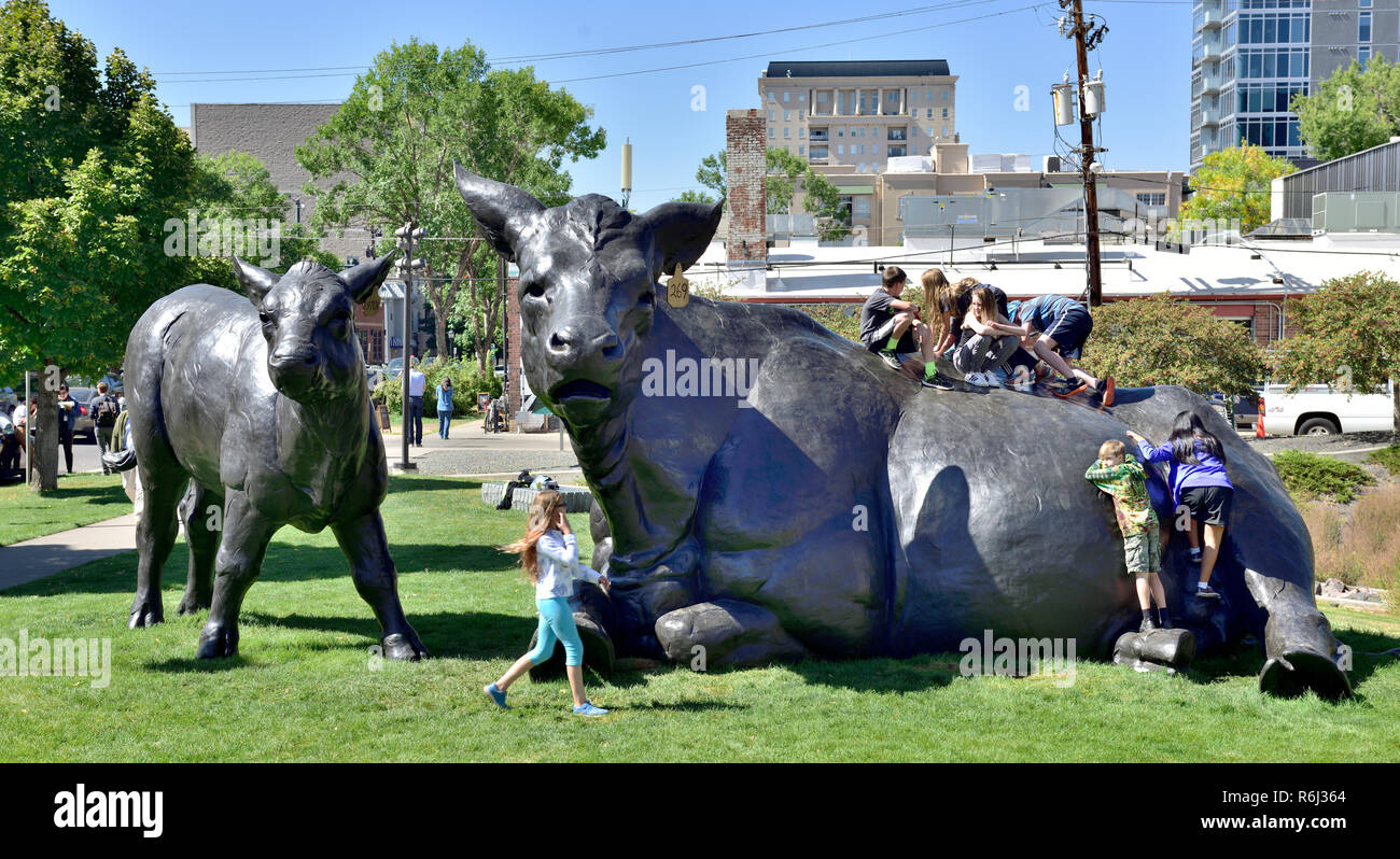 Kinder klettern auf und spielen mit der Skulptur cottish Angus Rind & Kalb" außerhalb des Denver Art Museum Stockfoto