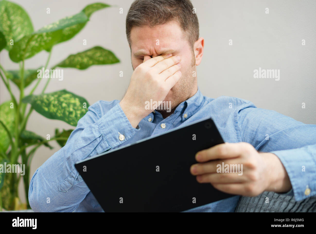 Stattliche unrasierte Mann reibt seine müden Augen. Stockfoto