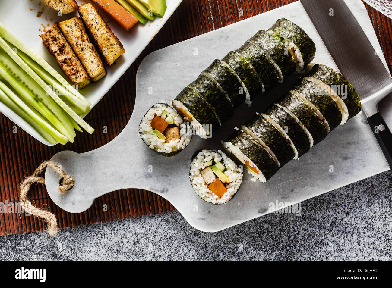 Vegan Ready-made Sushi auf dem Tisch in Fisch. Brötchen mit gebratenem Tofu, Gurken, gekochte Karotten und frischen Avocado. Gesunde vegane Ernährung Stockfoto