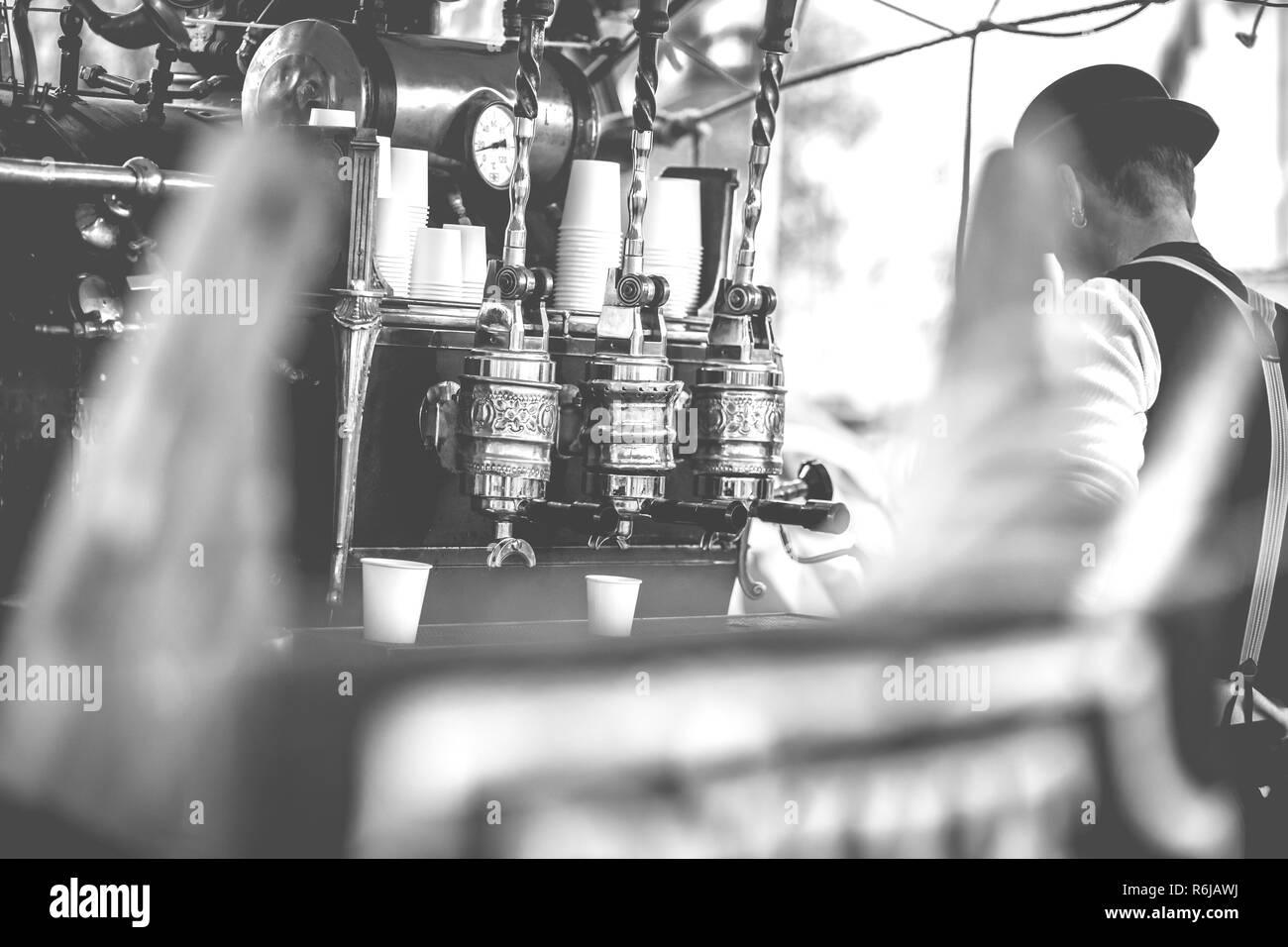 Vintage barista vorbereiten, um Kaffee zu Kunden im alten Stil Maschine mit handgefertigten Retro-look und throwback Kleidung in einen Marktstand Stockfoto