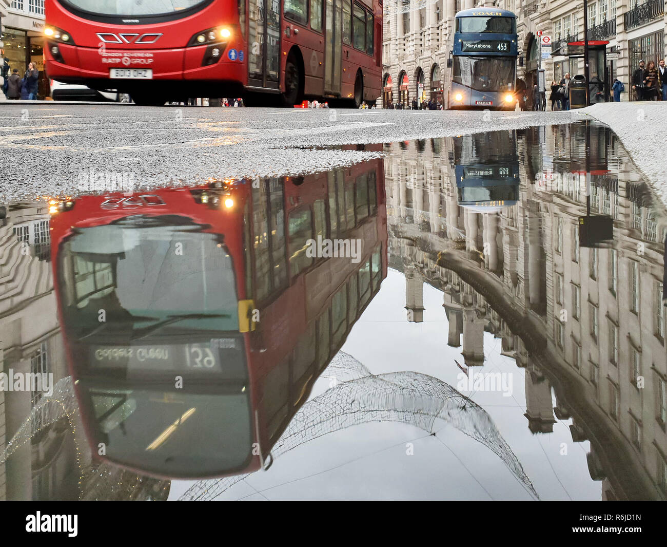 London, Großbritannien. 5 Dez, 2018. Eine Reflexion eines roten Londoner Doppeldeckerbus im Regent Street ist in einer großen Pfütze von Wasser gesehen. Credit: Dinendra Haria/SOPA Images/ZUMA Draht/Alamy leben Nachrichten Stockfoto