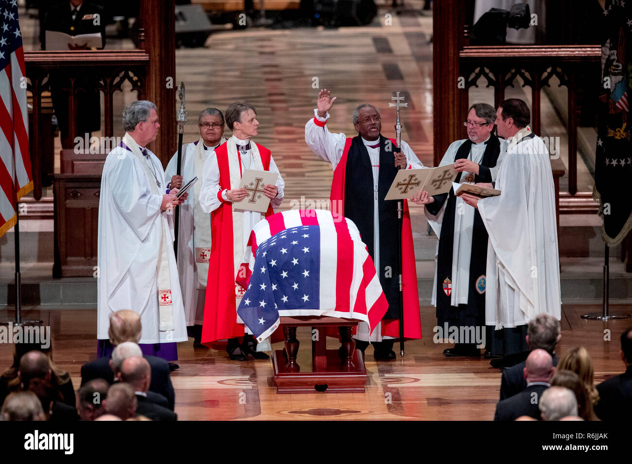 Mitglieder des Klerus stand über der Flagge - drapierte Schatulle des ehemaligen Präsidenten George H.W. Bush während seiner Staatsbegräbnis in der National Cathedral, Mittwoch, Dezember 5, 2018, in Washington. Credit: Andrew Harnik/Pool über CNP | Verwendung weltweit Stockfoto