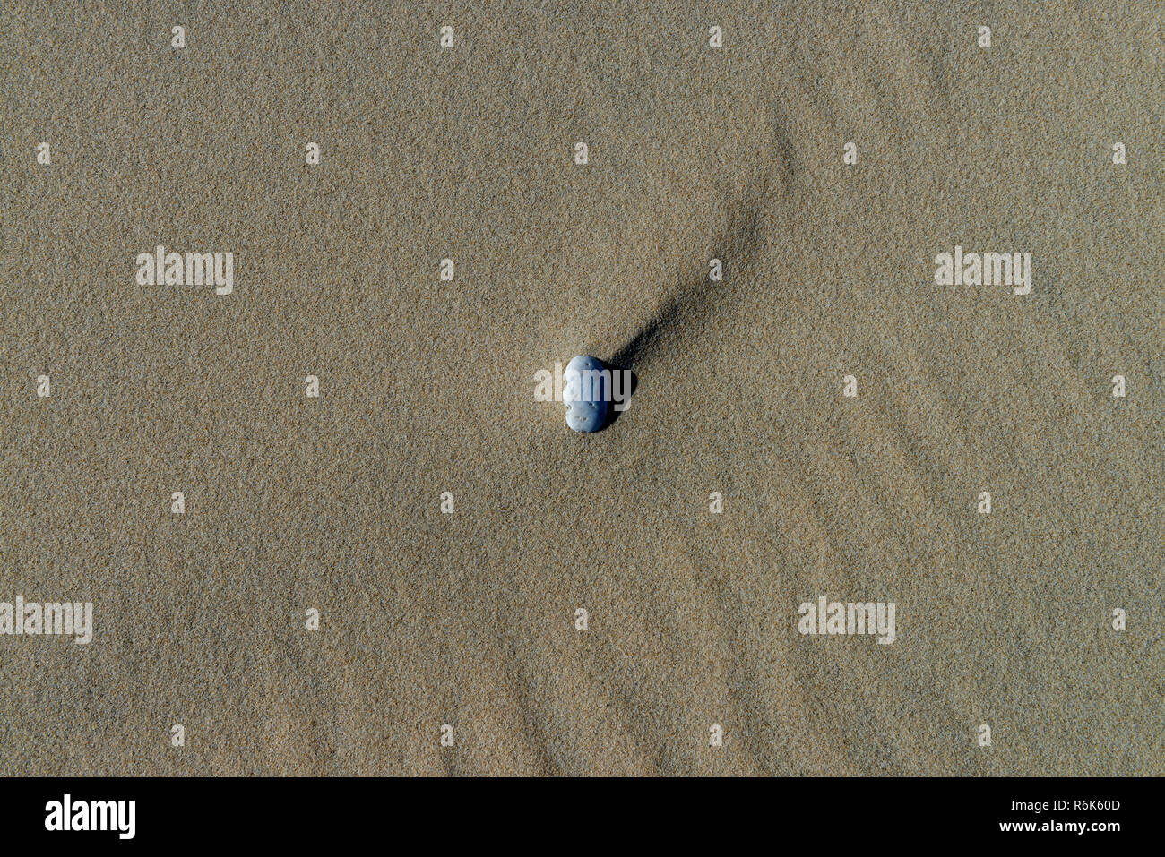 Isolierte Rock im Sand, ganz allein am Strand. Stockfoto