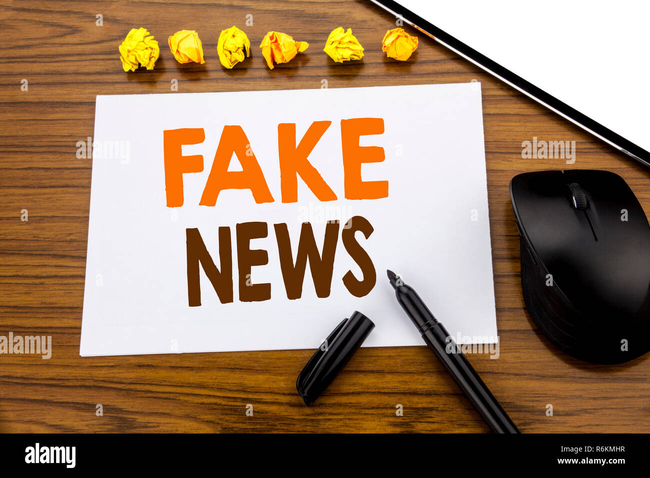 Konzeptionelle Hand Schreiben von Text mit gefälschten Nachrichten. Business Konzept für Hoax Journalismus auf haftnotiz Papier geschrieben auf dem hölzernen Hintergrund mit Marker mit der Maus und Tablet office anzeigen. Stockfoto