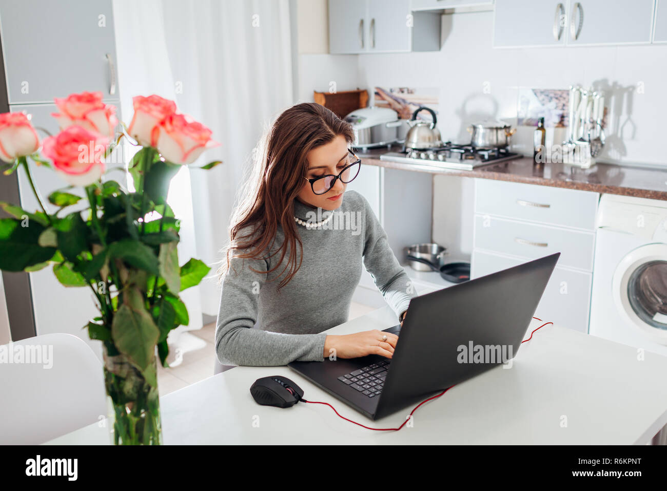 Frau Arbeiten am Laptop auf moderne Küche. Junge müde Freiberufler eingeben Stockfoto