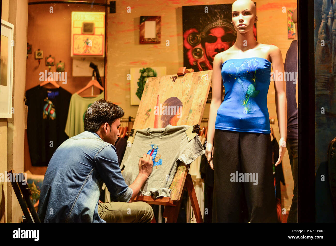 Ein Künstler macht eine handbemalte T-Shirt in einem Studio mit Schaufensterpuppe stehend an der Rückseite. Die Heimat vieler upstreet Cafés und Pubs, Hauz Khas Dorf ist Del Stockfoto