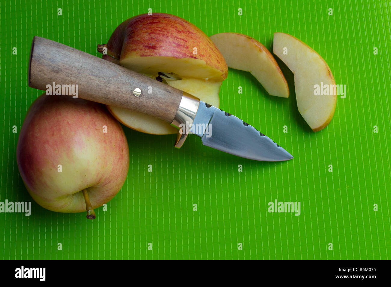 Handliches kleines Taschenmesser zum Schneiden leckere saftige Äpfel auf grüne Schneidbrett verwendet Stockfoto