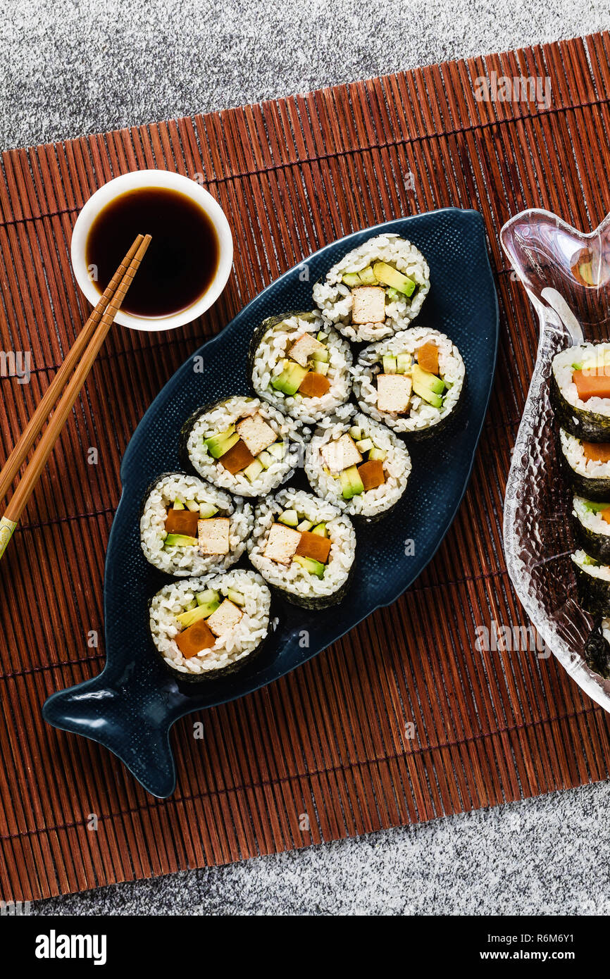 Vegan Ready-made Sushi auf dem Tisch in Fisch. Brötchen mit gebratenem Tofu, Gurken, gekochte Karotten und frischen Avocado. Gesunde vegane Ernährung Stockfoto