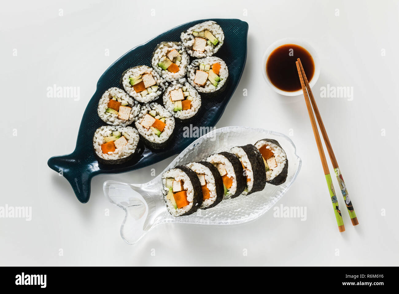 Vegan Ready-made Sushi auf dem Tisch in Fisch. Brötchen mit gebratenem Tofu, Gurken, gekochte Karotten und frischen Avocado. Gesunde vegane Ernährung Stockfoto