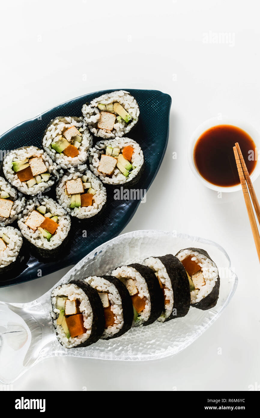Vegan Ready-made Sushi auf dem Tisch in Fisch. Brötchen mit gebratenem Tofu, Gurken, gekochte Karotten und frischen Avocado. Gesunde vegane Ernährung Stockfoto
