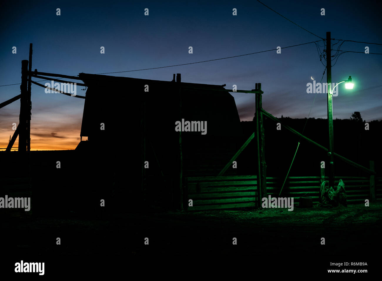 Ranch Scheune bei Sonnenaufgang Sonnenuntergang mit Mond im Hintergrund und fluoreszierendes Licht im Vordergrund. Stockfoto