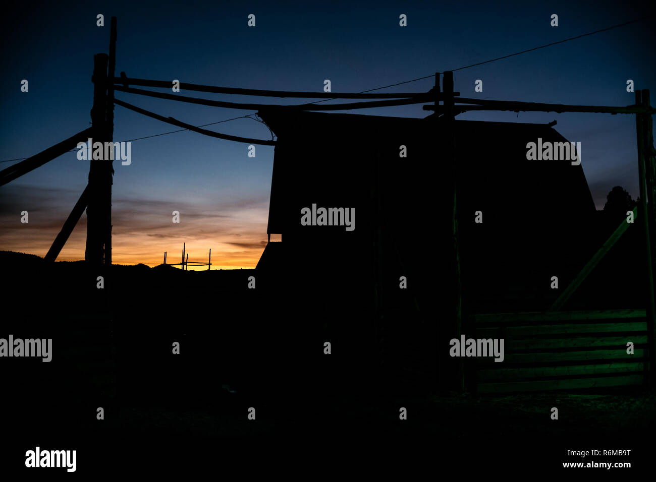 Ranch Scheune bei Sonnenaufgang Sonnenuntergang mit Mond im Hintergrund und fluoreszierendes Licht im Vordergrund. Stockfoto
