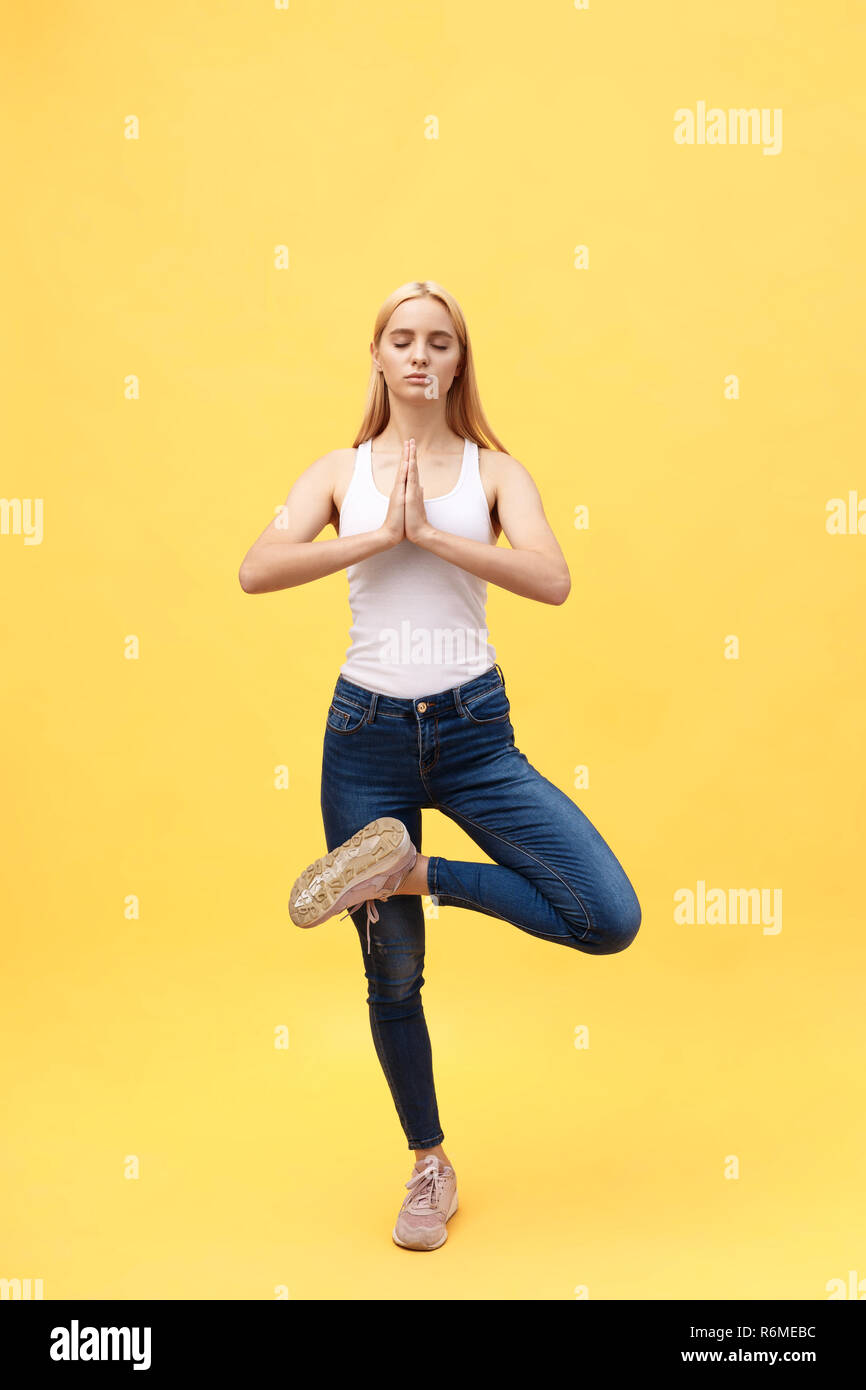 Sportlich attraktive junge Frau in Weiß Sportswear, Übung für Wirbelsäule, Vrikshasana darstellen, die Hände über dem Kopf in Anjali mudra, Teil des grossen Foto serie, isoliert, in voller Länge. Stockfoto