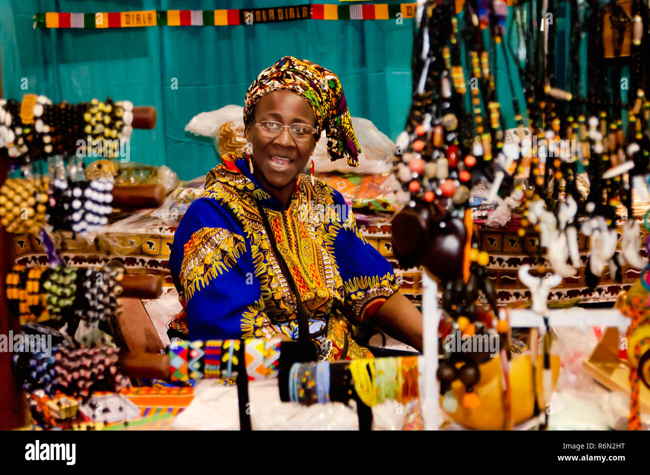 Ein Malinesischen Frau in Tracht gekleidet, sind Souvenirs auf der 34. jährlichen Mobile International Festival, Nov. 17, 2018 in Mobile, Alabama. Stockfoto