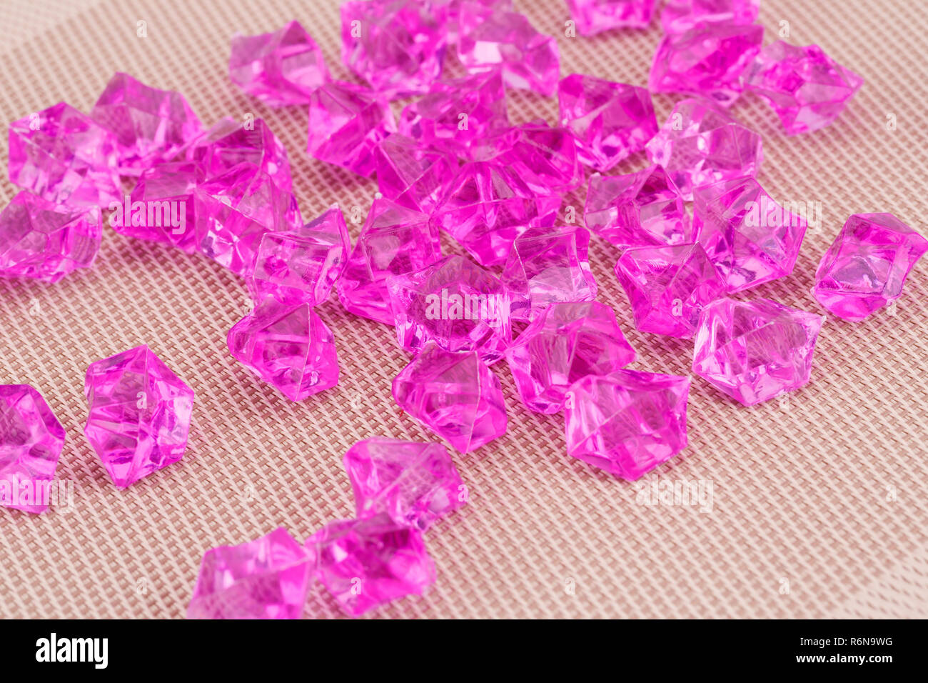 Rosa Kunststoff Steine auf beigem Hintergrund. Stockfoto