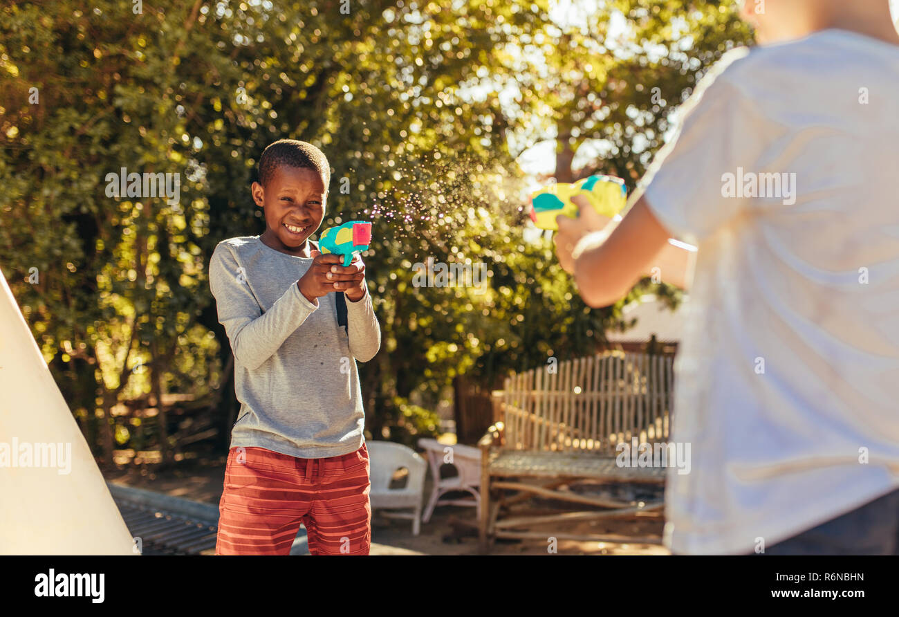 Zwei Kinder spielen mit Wasser Gewehren in den Hinterhof. Kinder spielt gerne mit sprizen Gewehren im Freien. Stockfoto
