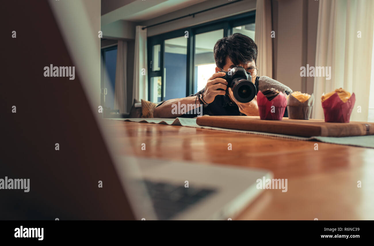 Männliche essen Fotograf blogger schießt Cupcakes auf Tisch. Essen Fotograf Bilder in seinem Studio. Stockfoto