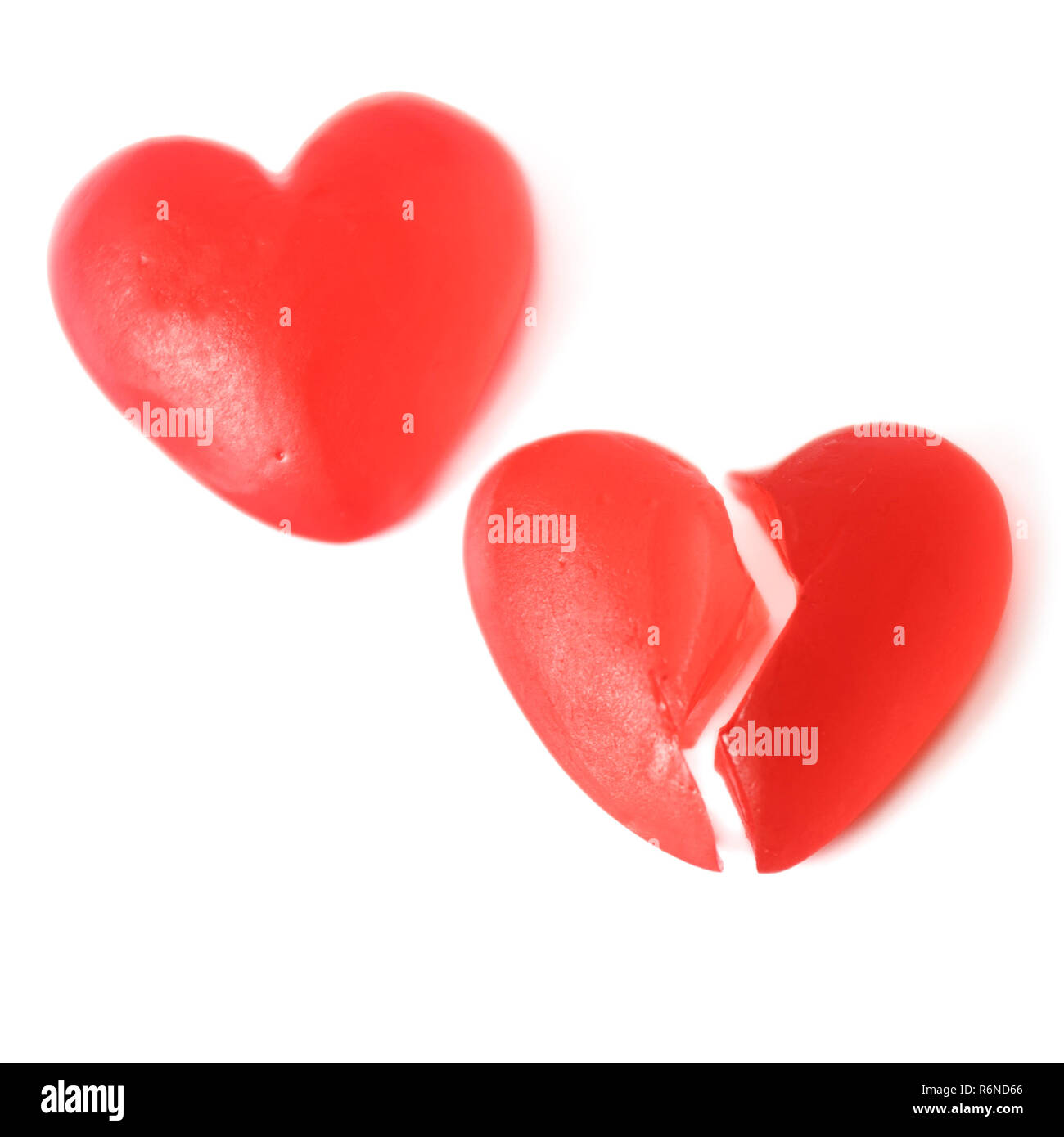 Gebrochene Herzen oder Kummer Konzept mit zwei hellen roten jelly Herz geformten Süßigkeiten nebeneinander mit einem Schnitt in der Hälfte auf weißem Hintergrund Stockfoto