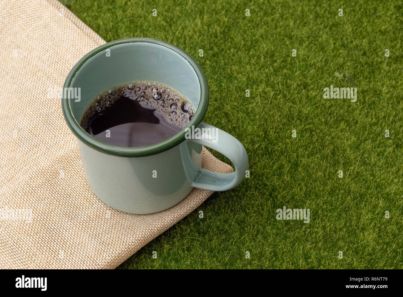 Kaffee in grün Tin Cup auf Gras Hintergrund. Stockfoto