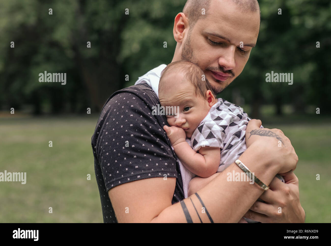 Junger Vater außerhalb schaukelnd seine niedlichen Baby Boy Stockfoto