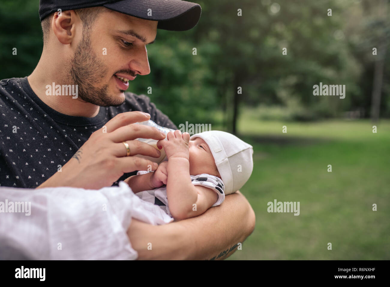 Lächelnd Vater, der sein Baby Boy außerhalb Füttern mit der Flasche Stockfoto