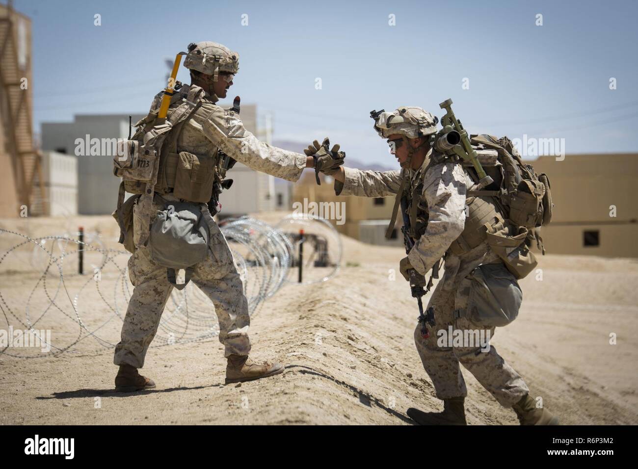 MARINE Corps Air Ground Combat Center Twentynine Palms, Kalifornien - Cpl. Cameron Halkovich (links), eine Bekämpfung der Ingenieur an 2nd Battalion, 7th Marine Regiment, unterstützt ein weiteres Marine auf einem steilen Hügel in einem städtischen Angriff bei 200 an Bord Marine Corps Air Ground Combat Center Twentynine Palms, Kalifornien, 16. Mai 2017. Die urbanen Kriegsführung Paket, Teil der integrierten Übung 3-17, ist ein platoon - Ebene Bataillon - Größe evolution wo Marines urban patrouillieren geübt, bis zu einem Marine Air Ground Task Force Angriff auf eine gegnerische Stadt gehalten. ITX ist ein Training evolution conduc Stockfoto