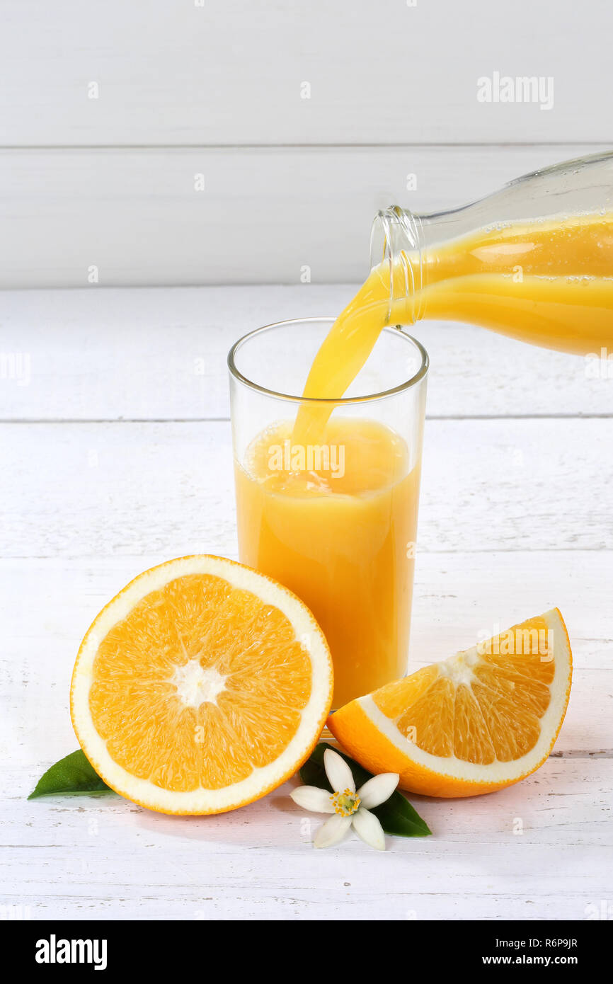 Orangensaft gießen in Gießen Orangensaft vertikales Format Flasche orange Saft ausgießen Stockfoto